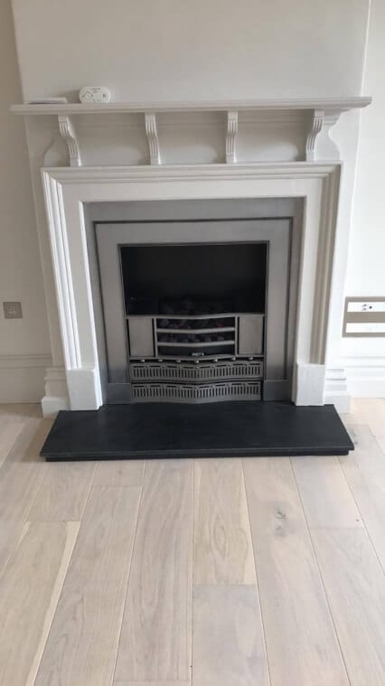 modern fireplace with white surround and shelving above